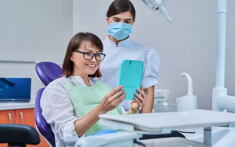 Patient Sitting In Dental Chair Looking At Mirror