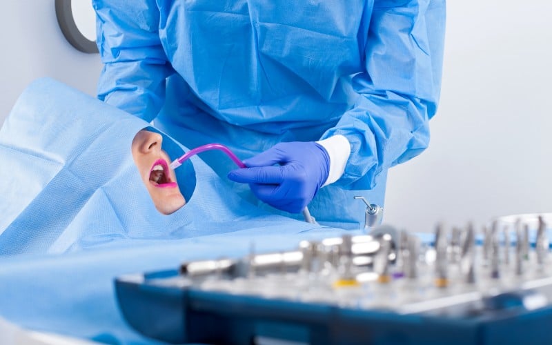 dentist blue uniform performing dental implant surgery