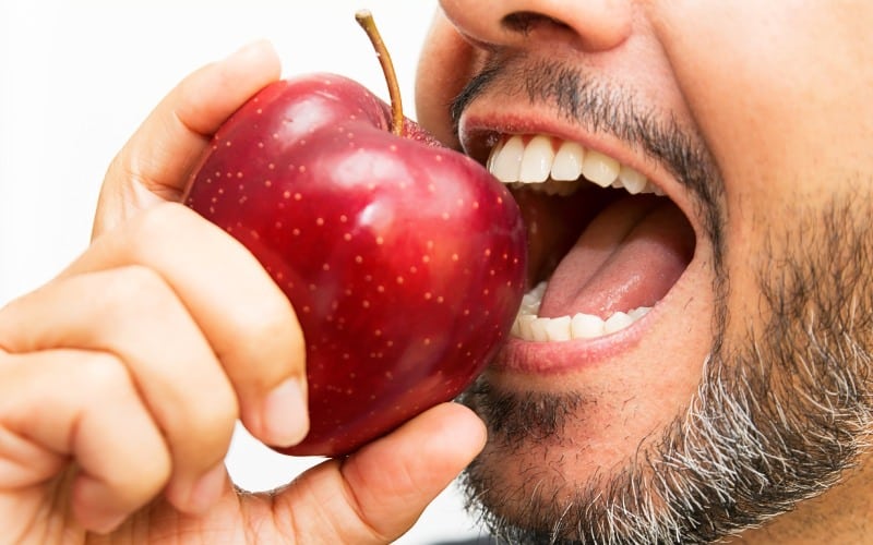 closeup of man with beard biting an apple