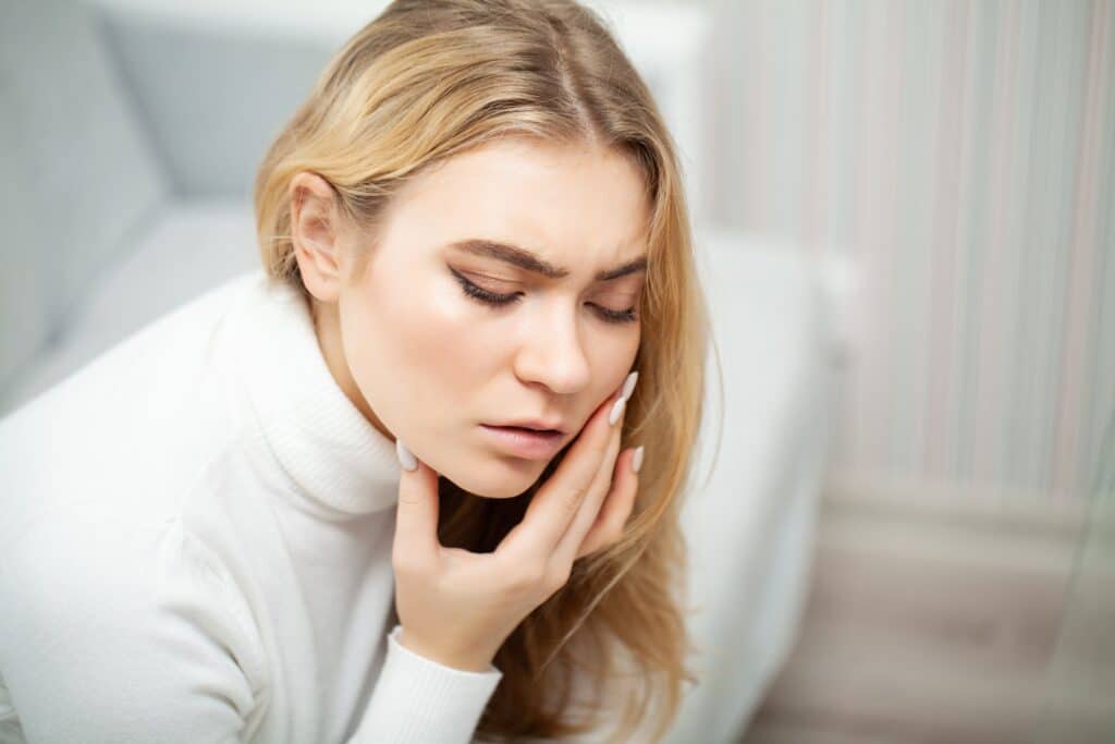 Tired woman keeping hand on her head.